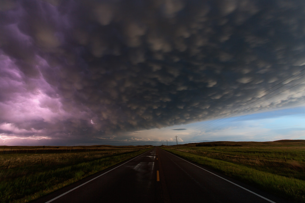 On a long, lonely highway between Merriman and Hyannis, Nebraska...a huge MCS moves by, leaving behind it wet roads and a gorgeous sky filled with mammatus clouds. A bit of lightning snakes around on the left side of the storm.