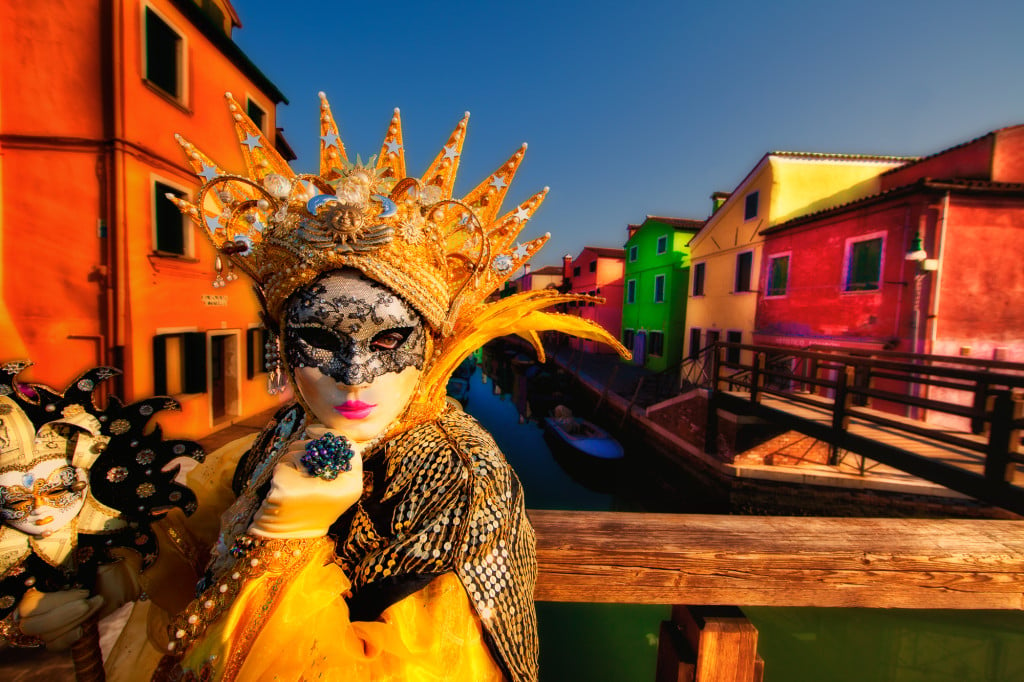 Yellow-costumed model on a bridge on Burano Island during Carnival