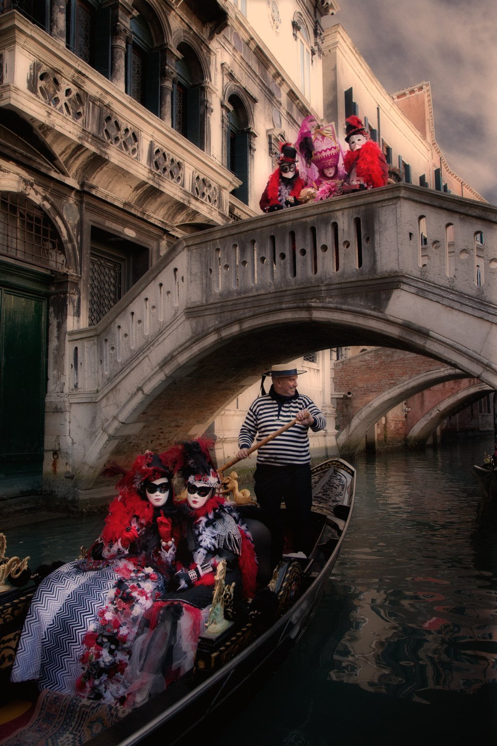 Carnival models riding in a gondola on a Venice canal