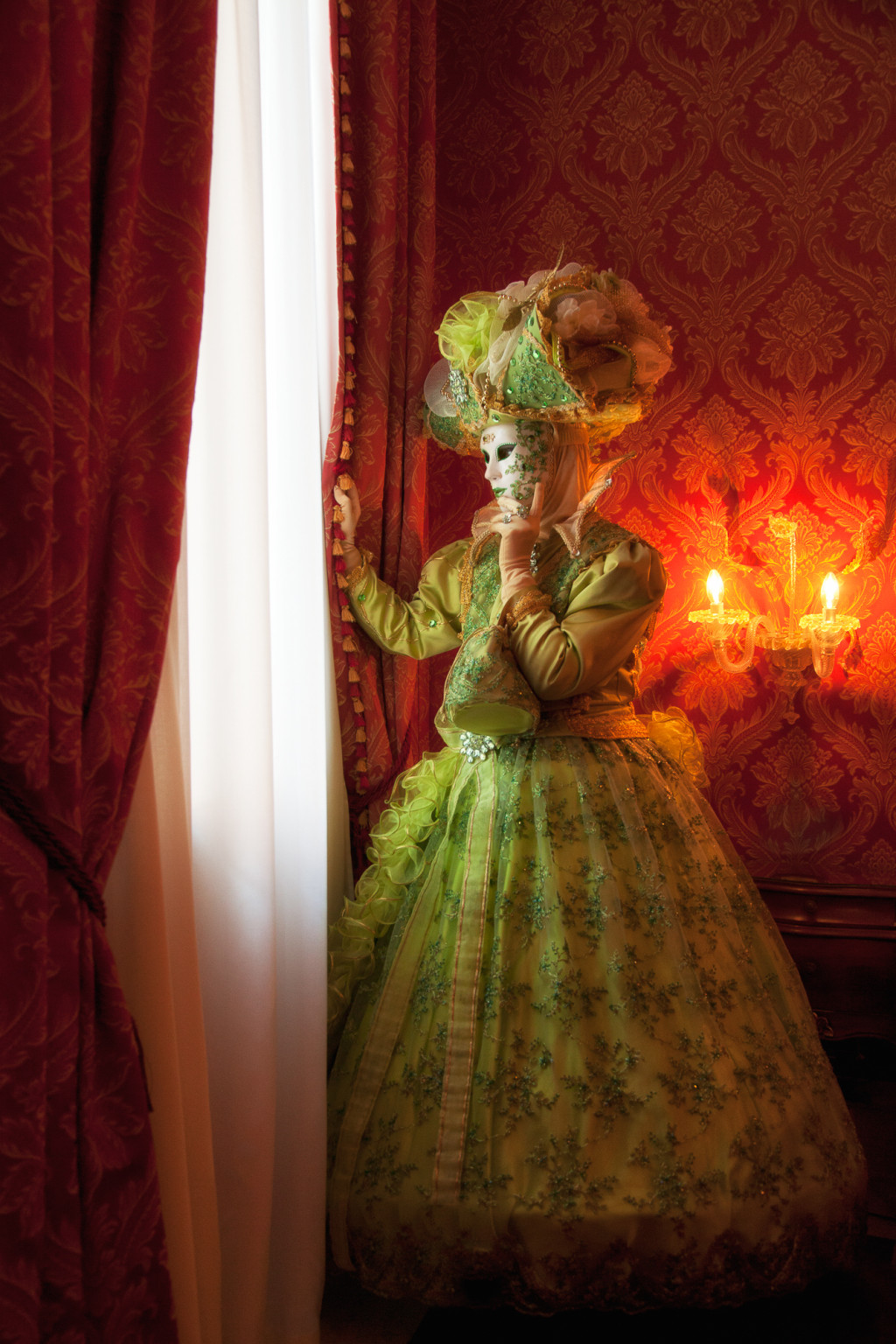 Green costumed model looking out of her hotel window in Venice