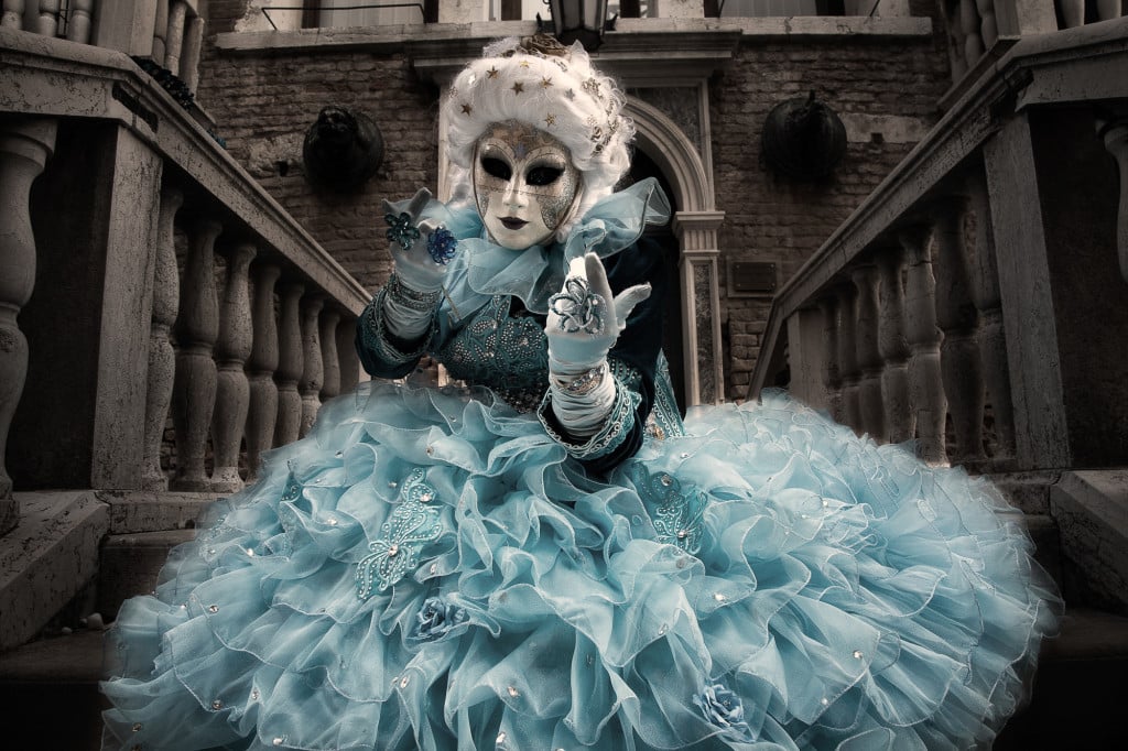 Blue costumed Carnival model calling from a stairway in Venice