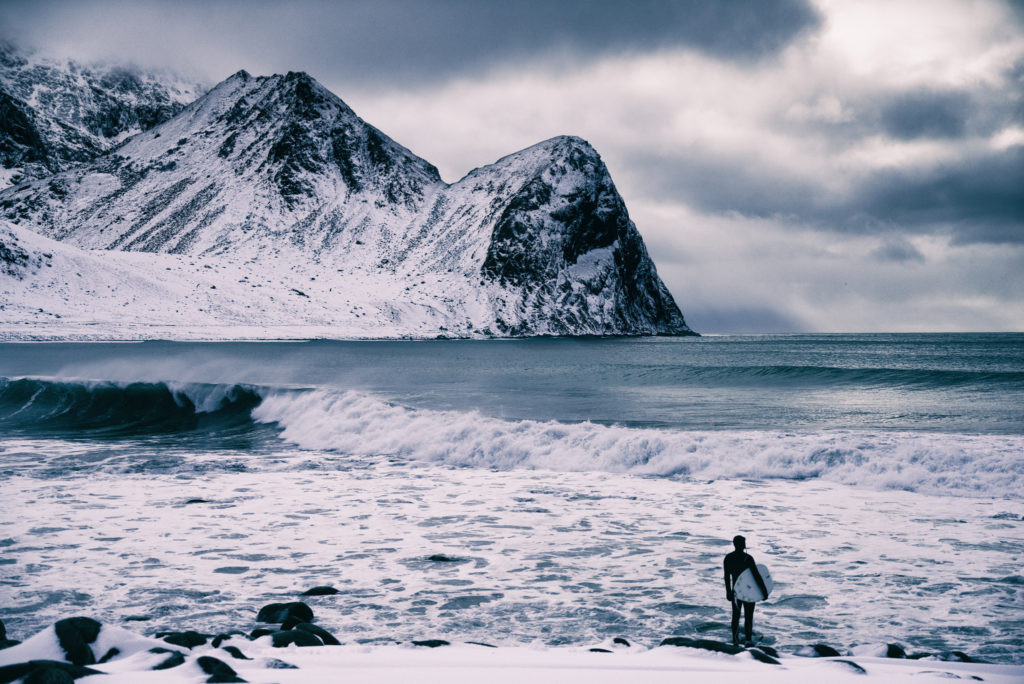 A surfer looks over the icy waters before jumping in for a session in Arctic Norway. Photo by Michael Bonocore. 